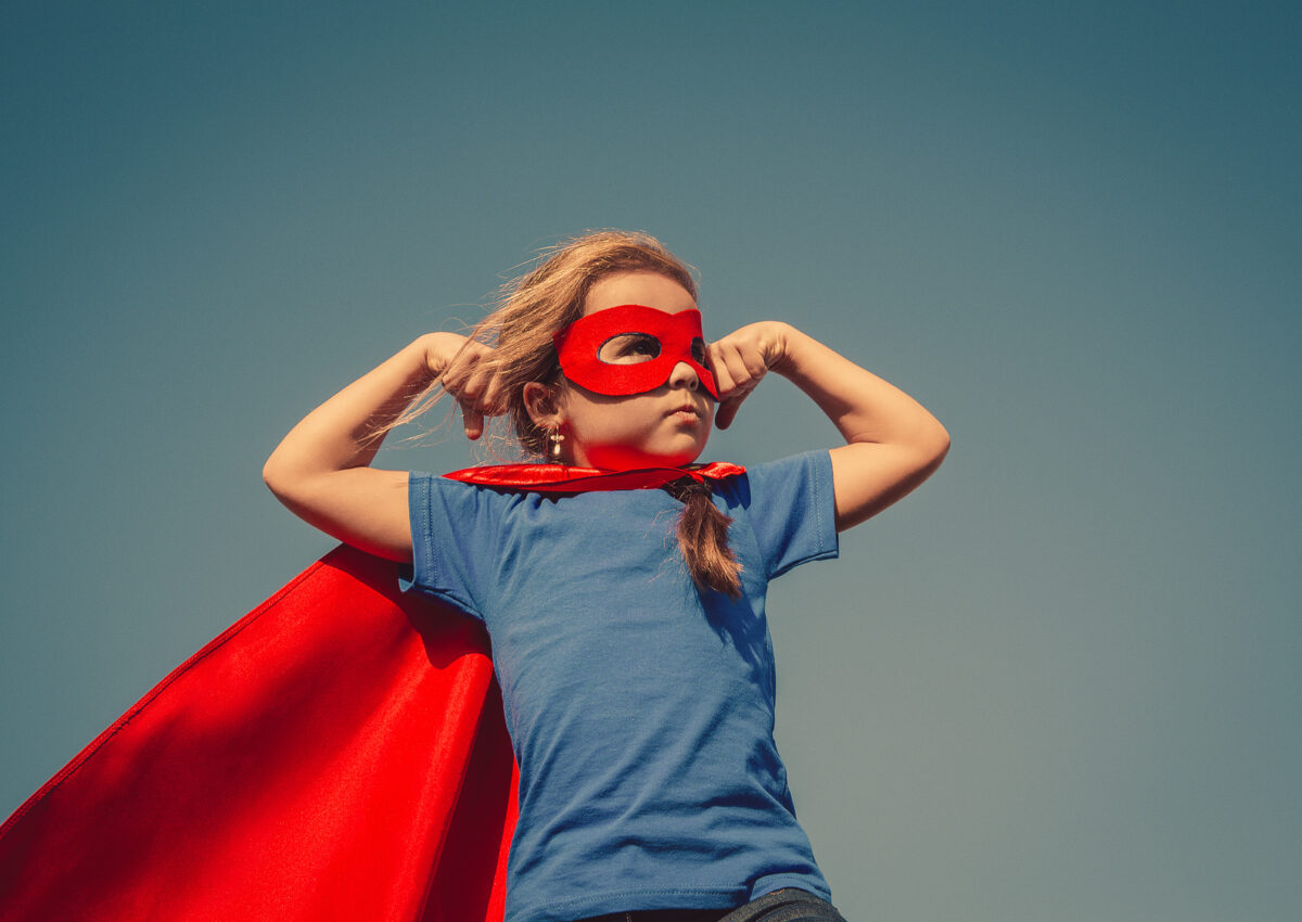 Funny little power super hero child (girl) in a red raincoat. Superhero concept. Instagram colors toning