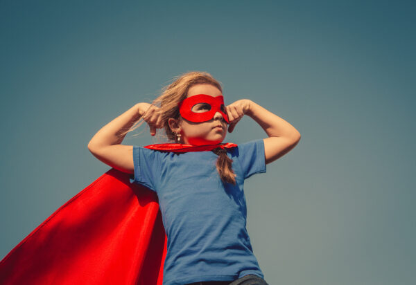 Child superhero portrait Funny little power super hero child (girl) in a red raincoat. Superhero concept. Instagram colors toning
