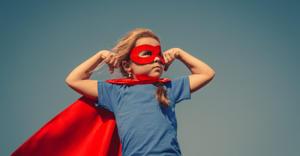 Child superhero portrait Funny little power super hero child (girl) in a red raincoat. Superhero concept. Instagram colors toning